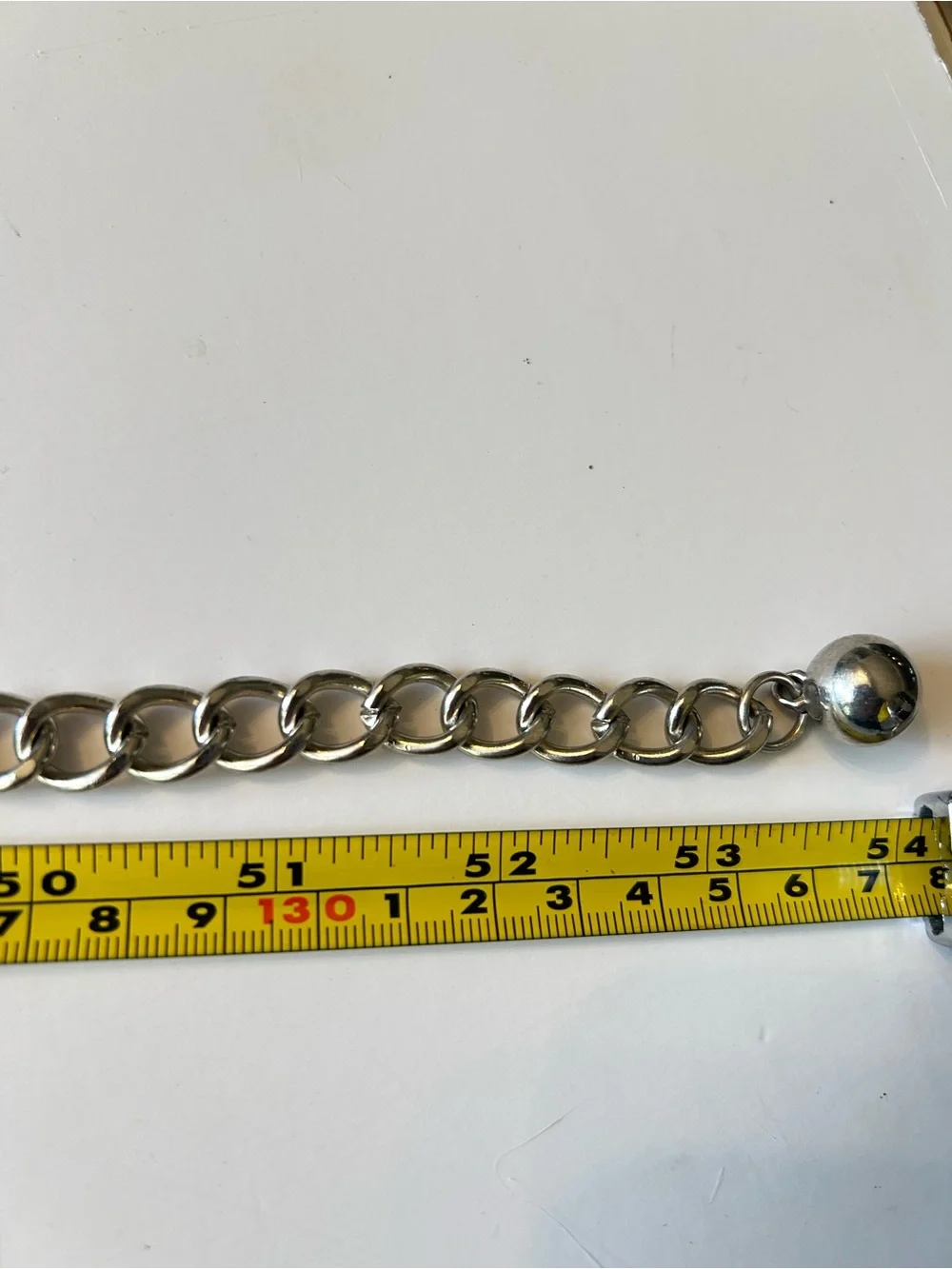 Silver-tone chain belt features textured medallion links and a hook closure L/XL